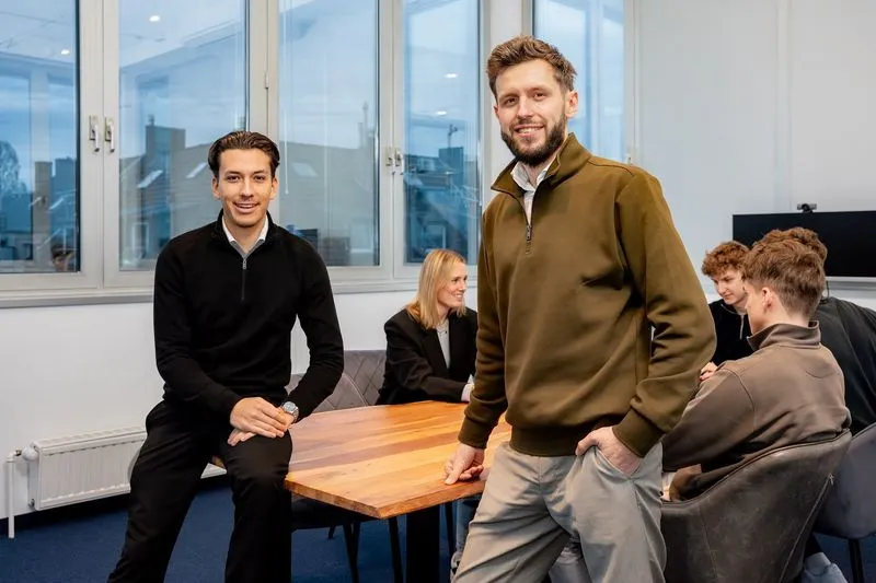 Zwei Teammitglieder von Rügamer & Steiner vor dem Team im Büro in Düsseldorf