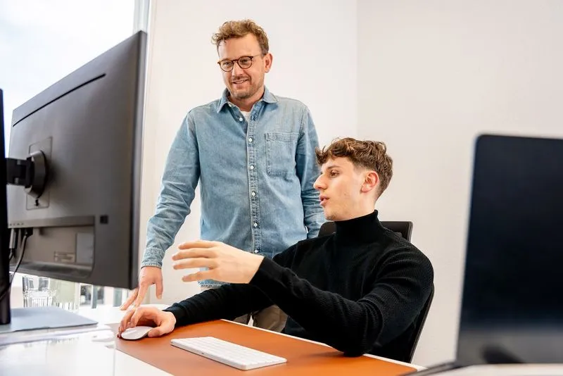 Zwei Kollegen besprechen ein Projekt am Bildschirm im Büro von Rügamer & Steiner