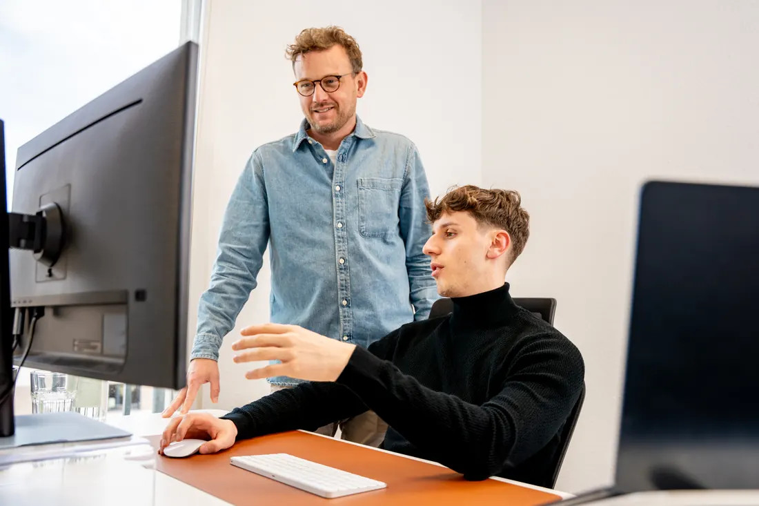 Zwei Kollegen besprechen ihre Arbeit am Bildschirm im Büro